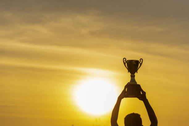 优胜者手握金冠奖杯杯奖。剪影最佳奖胜利手捧奖杯职业冠军挑战队捧金质体育奖杯杯。双赢运动团队理念图片下载