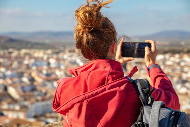 一名女子正在用智能手机拍摄城市照片图片下载