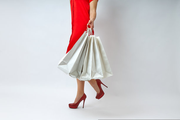 美丽的腿的年轻女子与购物袋在一个白色的背景图片下载