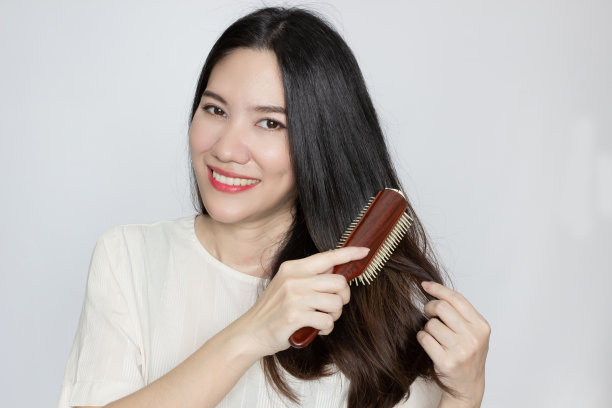 亚洲美女正梳着头发，带着幸福和微笑。图片下载