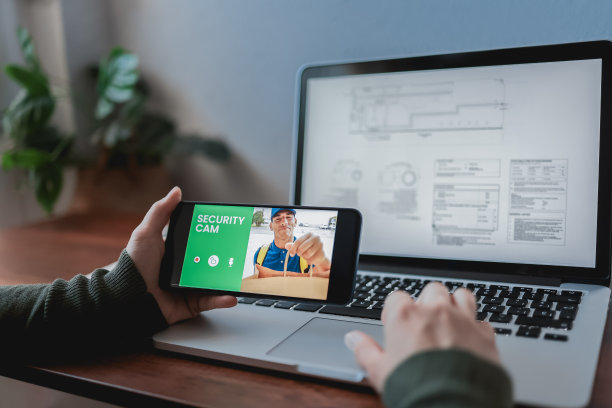 一名妇女用手机上的闭路电视安全摄像头监视送货员按门铃-家庭安全图片下载