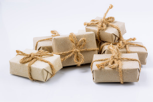 一套用牛皮纸手工制作的礼物，用粗麻绳扎着，用干花装饰在白色的桌子上。俯视图图片下载
