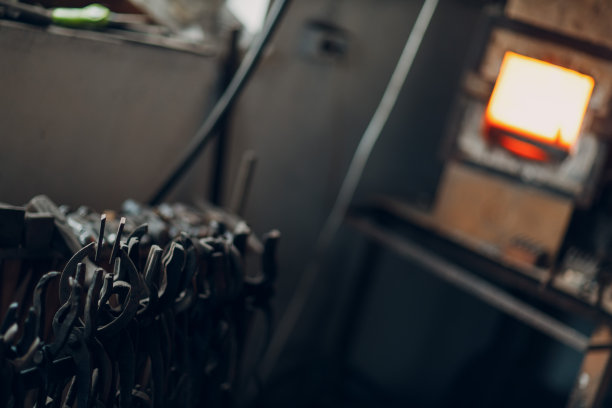 铁匠用炽热的火焰锻造炉子。史密斯在红热锻炉的火中加热铁块图片下载