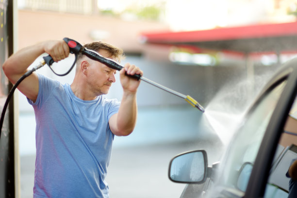 洗车。成年男子用高压射流清洗汽车。图片下载