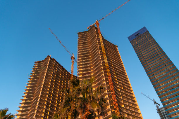 夕阳下的蓝天映衬着正在施工的多层建筑和起重机图片下载