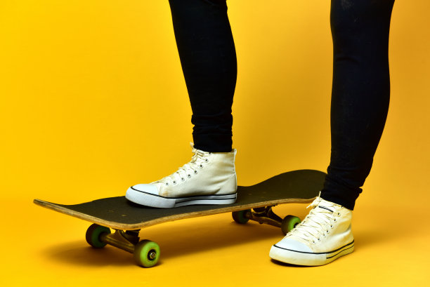 滑冰女孩的腿穿着白色运动鞋在黄色的背景。图片下载