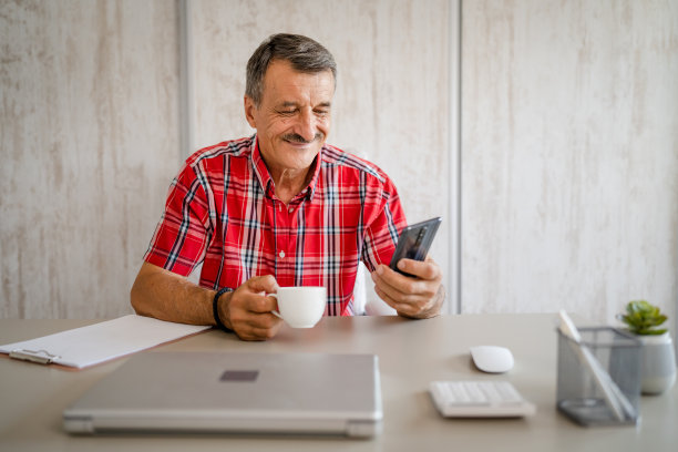 老男人在工作时端着咖啡和手机图片下载