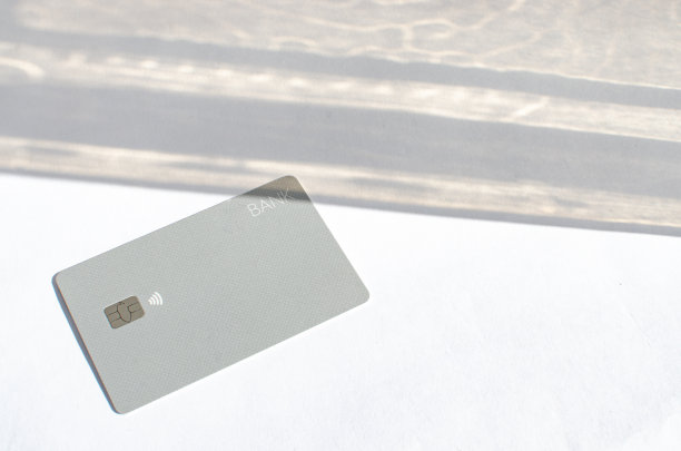 塑料信用卡与芯片可见，在桌上与柔和的灯光和阴影。白色表面的灰色卡片。概念:金融、购买、支付、贷款、支出、投资和债务。图片下载