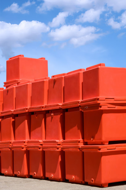 蓝色的天空下，仓库外的院子里堆放着一组橙色的可折叠冰桶图片下载