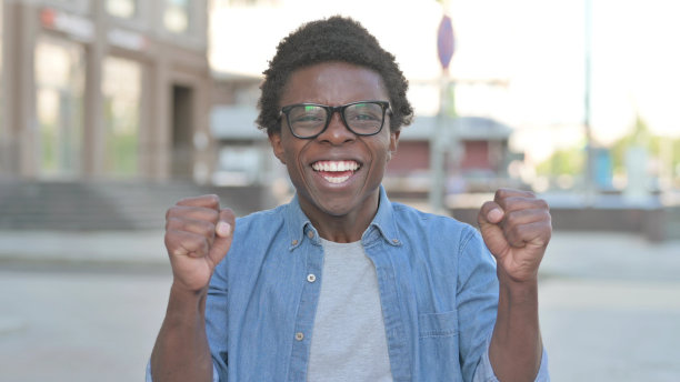 兴奋的非洲青年在户外庆祝成功图片下载