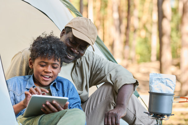 旅行期间，快乐的小男孩用平板电脑浏览网上照片图片下载