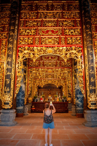 一名年轻女子在越南宁平的不可思议的寺庙用手机拍照图片下载