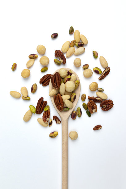 将去皮的坚果放入木勺中混合，分离在白色上图片下载