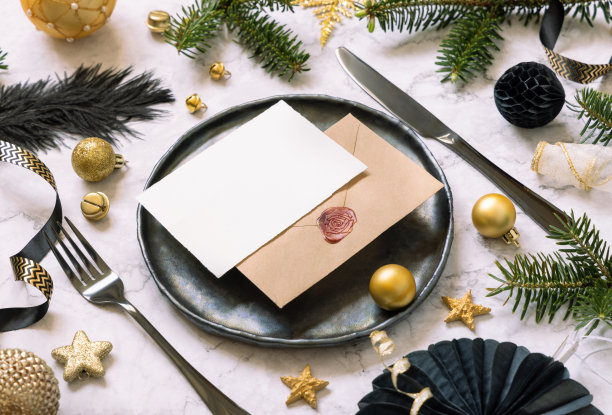 黑色和金色的圣诞餐桌设置与卡片，饰品和杉树树枝。模型图片下载