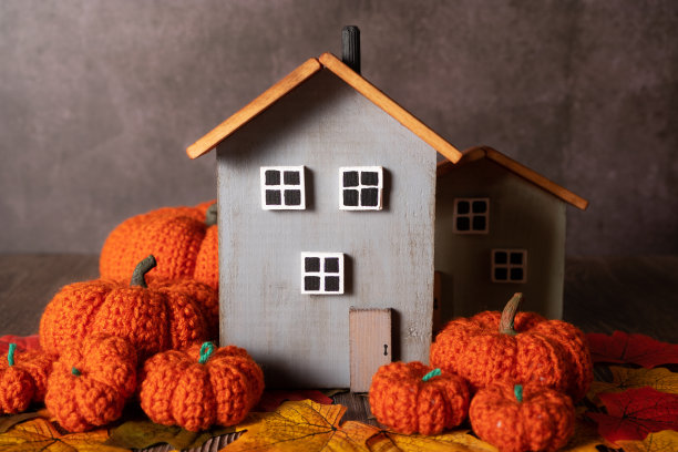 一幢灰色的装饰性木屋矗立在编织的南瓜中。秋天的概念图片下载