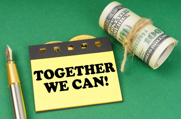 在绿色的表面上是一支笔，美元和黄色的贴纸，上面写着“团结起来，我们可以”图片下载