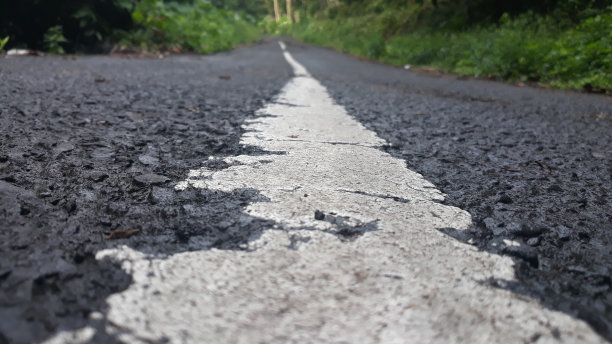 街道沥青裂缝纹理和街道中间的白色油漆标志图片下载