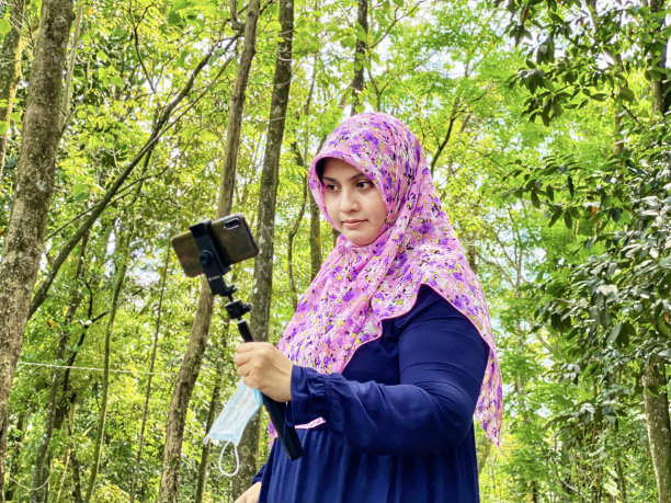 喜欢摄影的戴着头巾的女子在城市森林里用智能手机看照片图片下载