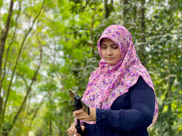 喜欢摄影的戴着头巾的女子在城市森林里用智能手机看照片图片下载