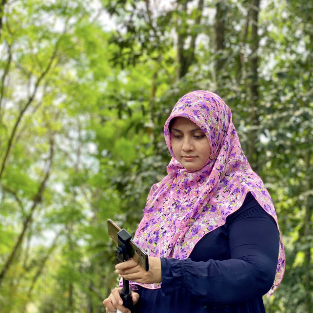 喜欢摄影的戴着头巾的女子在城市森林里用智能手机看照片图片下载