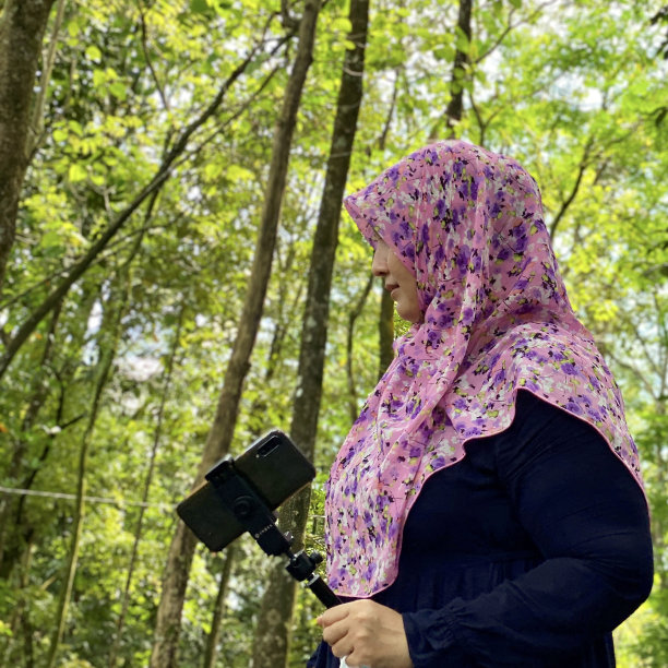 喜欢摄影的戴着头巾的女子在城市森林里用智能手机看照片图片下载