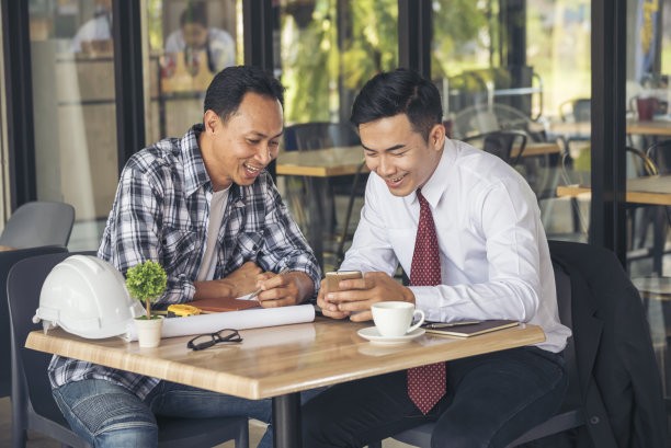 亚洲工程师头脑风暴建筑承包商土木工人伙伴团队会议在施工现场。图纸工程师，安全帽工人，头盔放在桌子上。工程师团队合作咨询图片下载