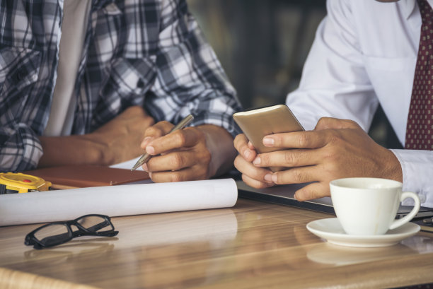 亚洲工程师头脑风暴建筑承包商土木工人伙伴团队会议在施工现场。图纸工程师，安全帽工人，头盔放在桌子上。工程师团队合作咨询图片下载