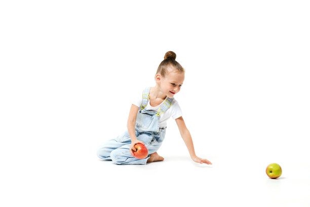 可爱的女孩穿着牛仔工装裤，白色背景上有苹果。图片下载