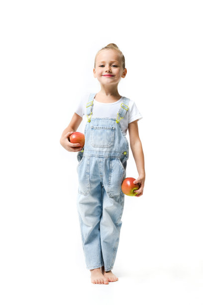 可爱的女孩穿着牛仔工装裤，白色背景上有苹果。图片下载