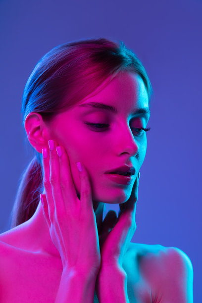 氖辉光。年轻可爱的女孩保持良好的皮肤和裸露的肩膀孤立在粉红色霓虹灯的黑暗背景。艺术、时尚、风格、灵感的概念图片下载