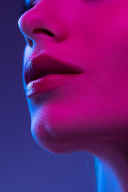 特写女性的嘴唇，脸颊和鼻子孤立在霓虹灯的黑暗背景。美容概念，护肤，化妆品，整形手术，广告图片下载