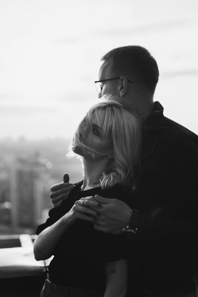 浪漫的白人夫妇穿着时髦的衣服在屋顶上享受风景和时间在一起。图片下载