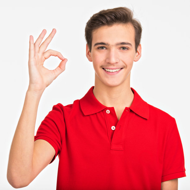 肖像的快乐的年轻人显示好的姿态，孤立的白色背景。微笑的照片英俊的白人男子在一件红衬衫与签名OK。积极的男性表示好的。图片下载