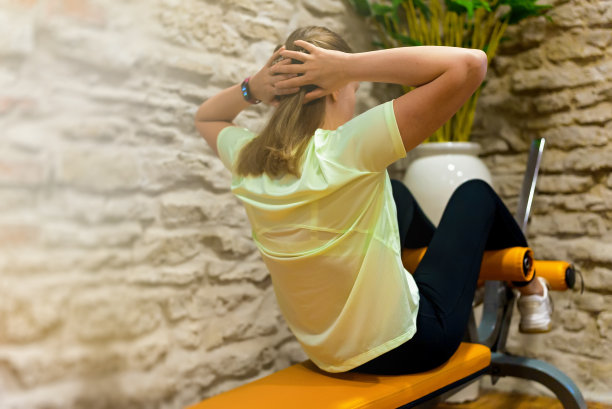 女子在健身房的长凳上做ABS运动。图片下载