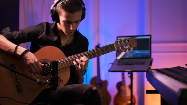 戴着耳机的音乐家在音乐工作室用专业的音频麦克风录制他的作品。图片下载