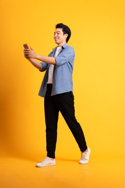 亚洲男子在黄色背景上摆姿势的全身图像图片下载