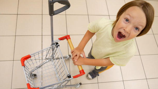 特写一个有趣的尖叫男孩与一个小空购物车图片下载