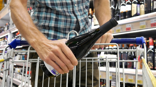 酒水部的购物车特写，一个男人把一瓶漂亮的葡萄酒放进去图片下载