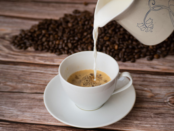 把牛奶倒进一杯白色的咖啡里。图片下载