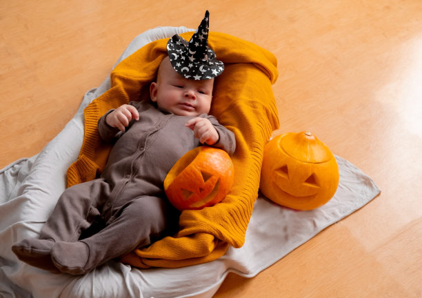 可爱的新生儿生活肖像。婴儿躺在有雕刻南瓜的针织毯子上。图片下载