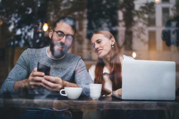 快乐的情侣在咖啡馆用智能手机聊天图片下载