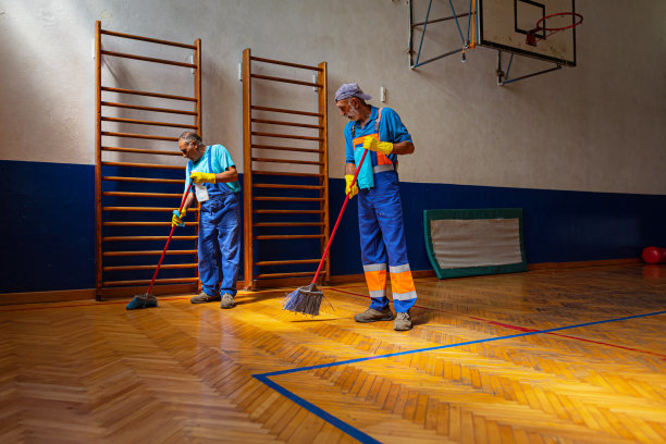 两个年长的男清洁工正在体育馆打扫地板图片下载