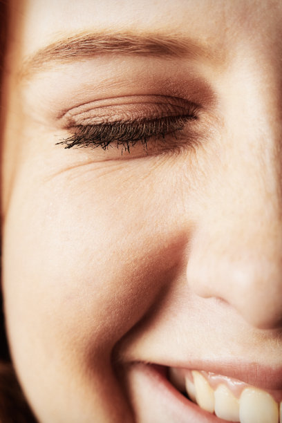 宁静的年轻女子微笑着，她的眼睛闭着，在她的脸的极端特写镜头图片下载