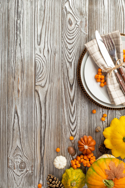 感恩节的概念。俯视图垂直照片的桌子设置盘子餐巾餐具生蔬菜南瓜pattypans松果罗文枫叶和橡子孤立的灰色木制桌子背景图片下载