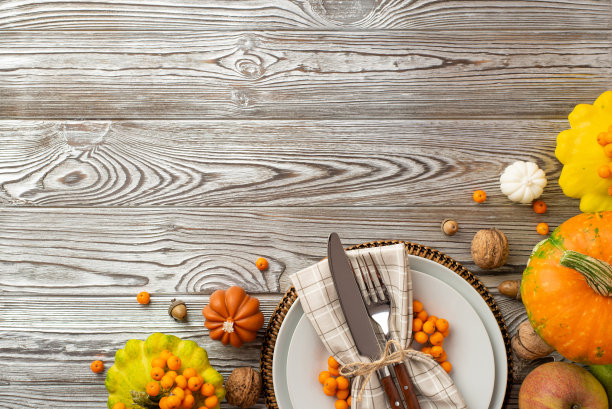 感恩节的概念。俯视图照片的餐桌设置盘子餐巾餐具新鲜蔬菜南瓜pattypans苹果罗梨浆果坚果橡子孤立的灰色木桌背景与copyspace图片下载