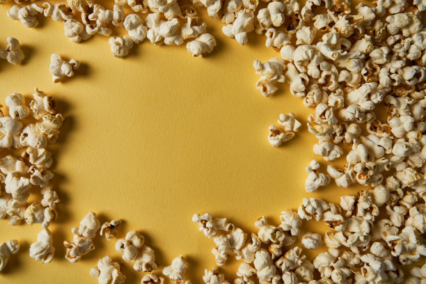 黄色背景的爆米花。副本的空间。流行玉米集合。不同大小的爆米花图片下载