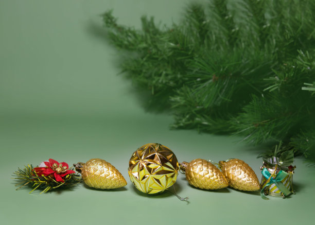 在绿色的背景上，有几排圣诞树玩具在后面，你可以看到一个人造云杉树枝作为文字的地方图片下载