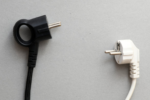 灰色背景上的黑白电插头。商业概念，电流成本上升。图片下载