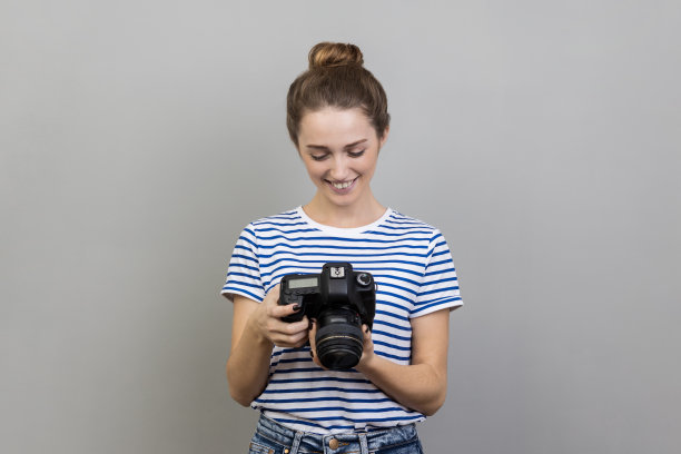 满意的女旅行者或摄影师拿着相机，看着相机，拍照。图片下载