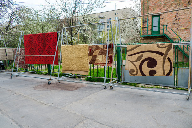 不同的地毯挂在户外的架子上。专业地毯清洗和烘干图片下载